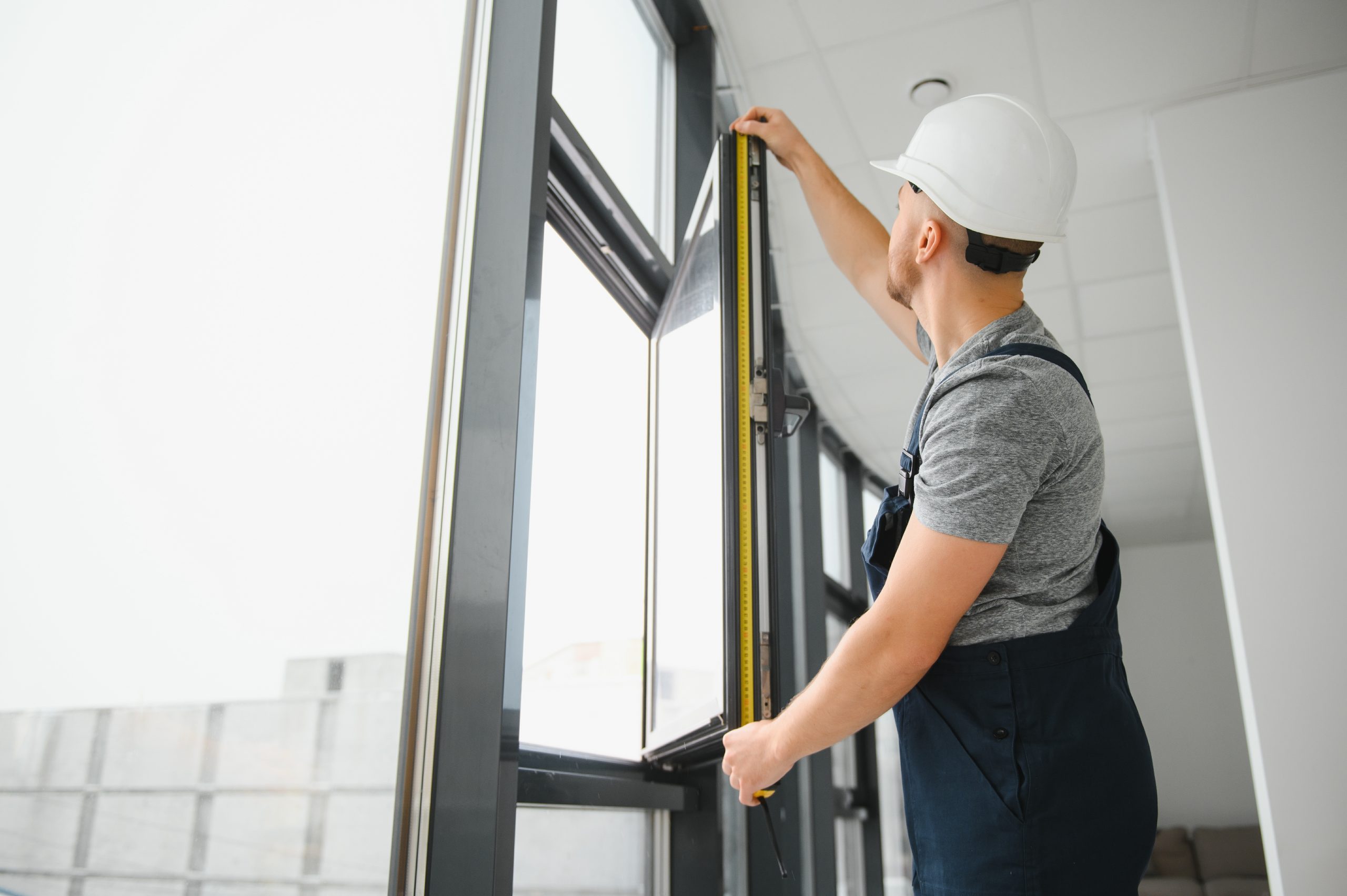 Construction worker repairing plastic window with screwdriver indoors, space for text. Banner design